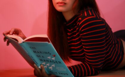 woman in striped long sleeve shirt holding a book